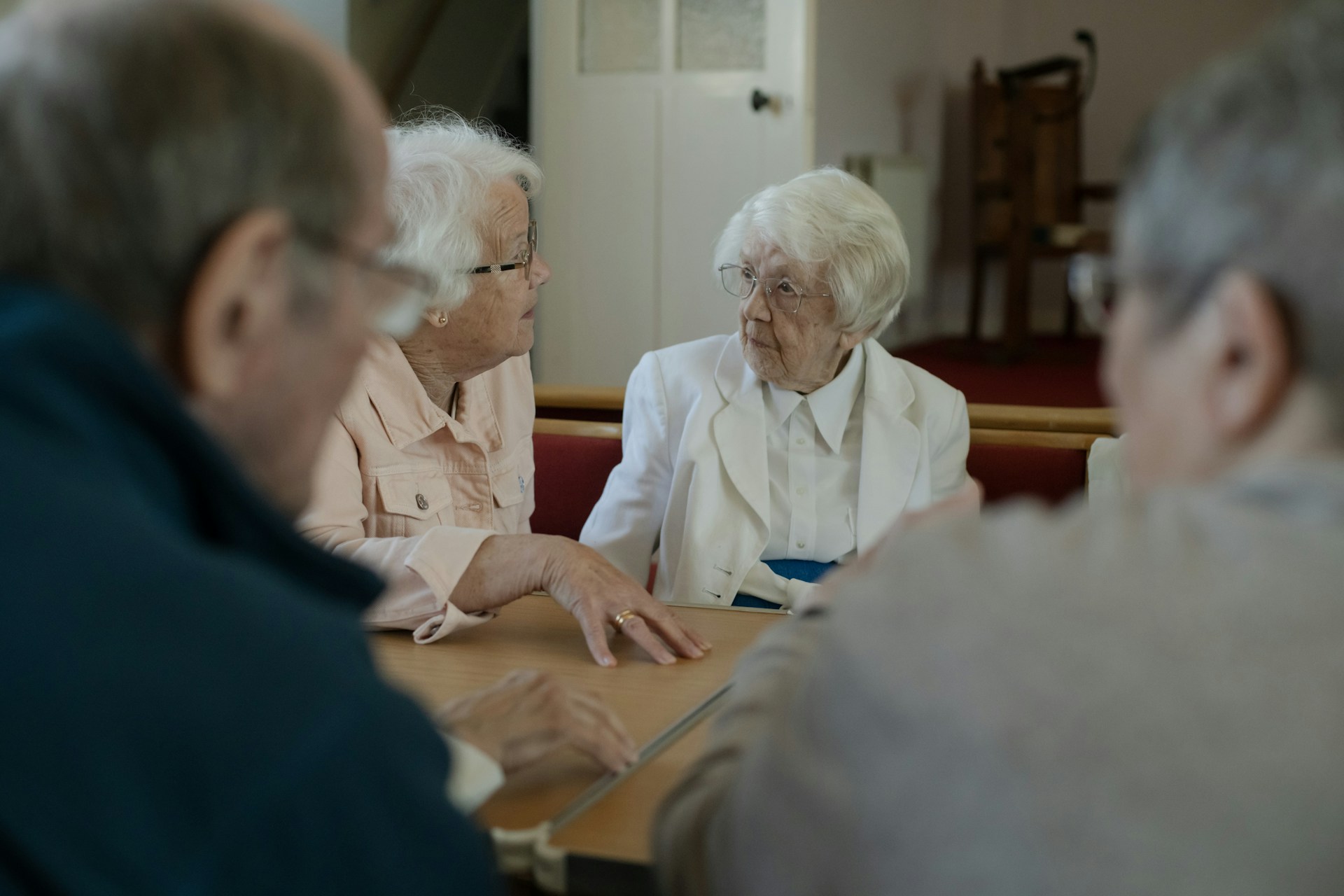 Seniors are sitting around a table, talking.