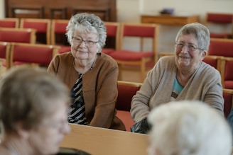 Two elderly women sit in a church.