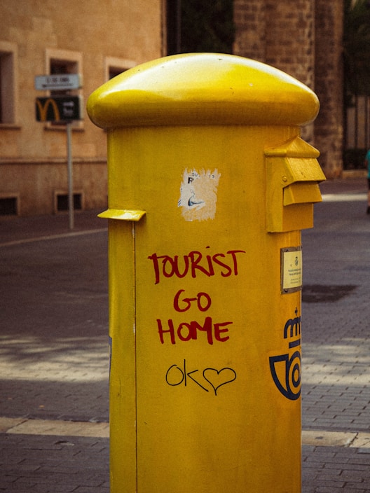 Yellow mailbox with anti-tourist graffiti about Mallorca overtourism