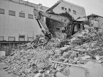 An excavator dismantles a building into a rubble pile.