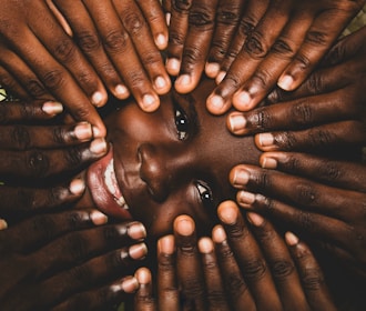 A child surrounded by hands, peeking through.