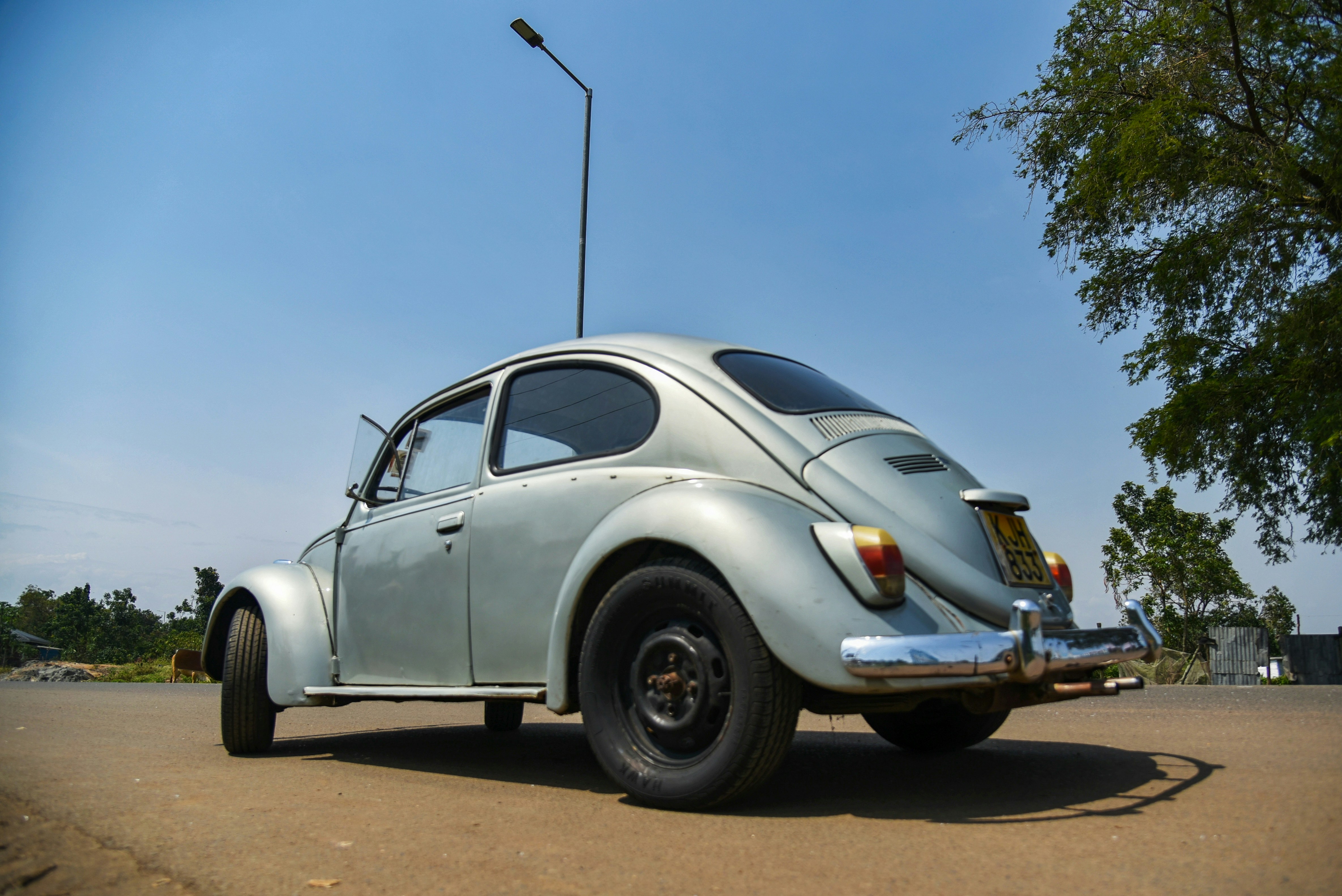 Ein klassischer silberner VW Käfer, der im Freien geparkt ist.