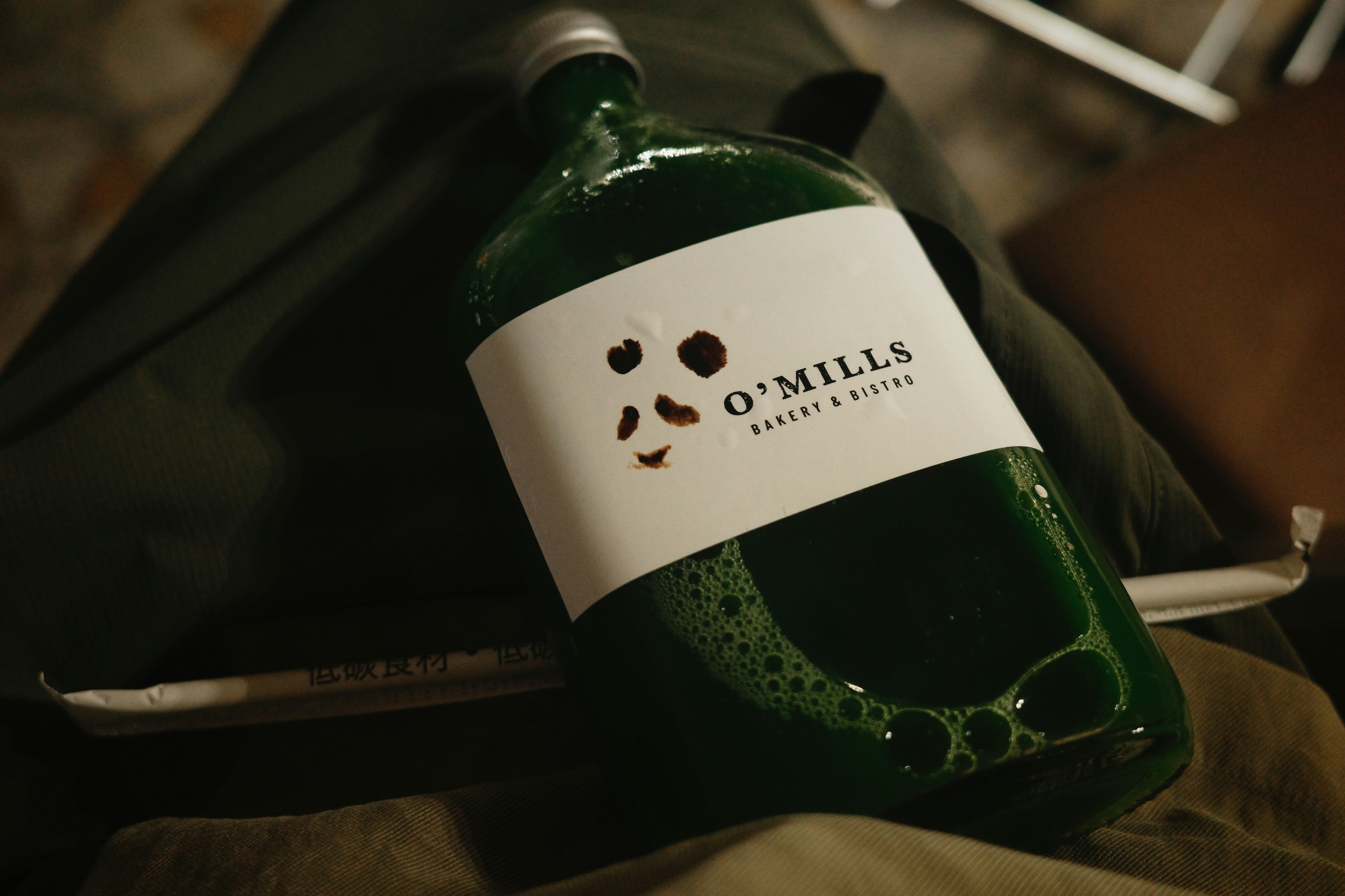 Green bottle of drink from o'mills bakery.