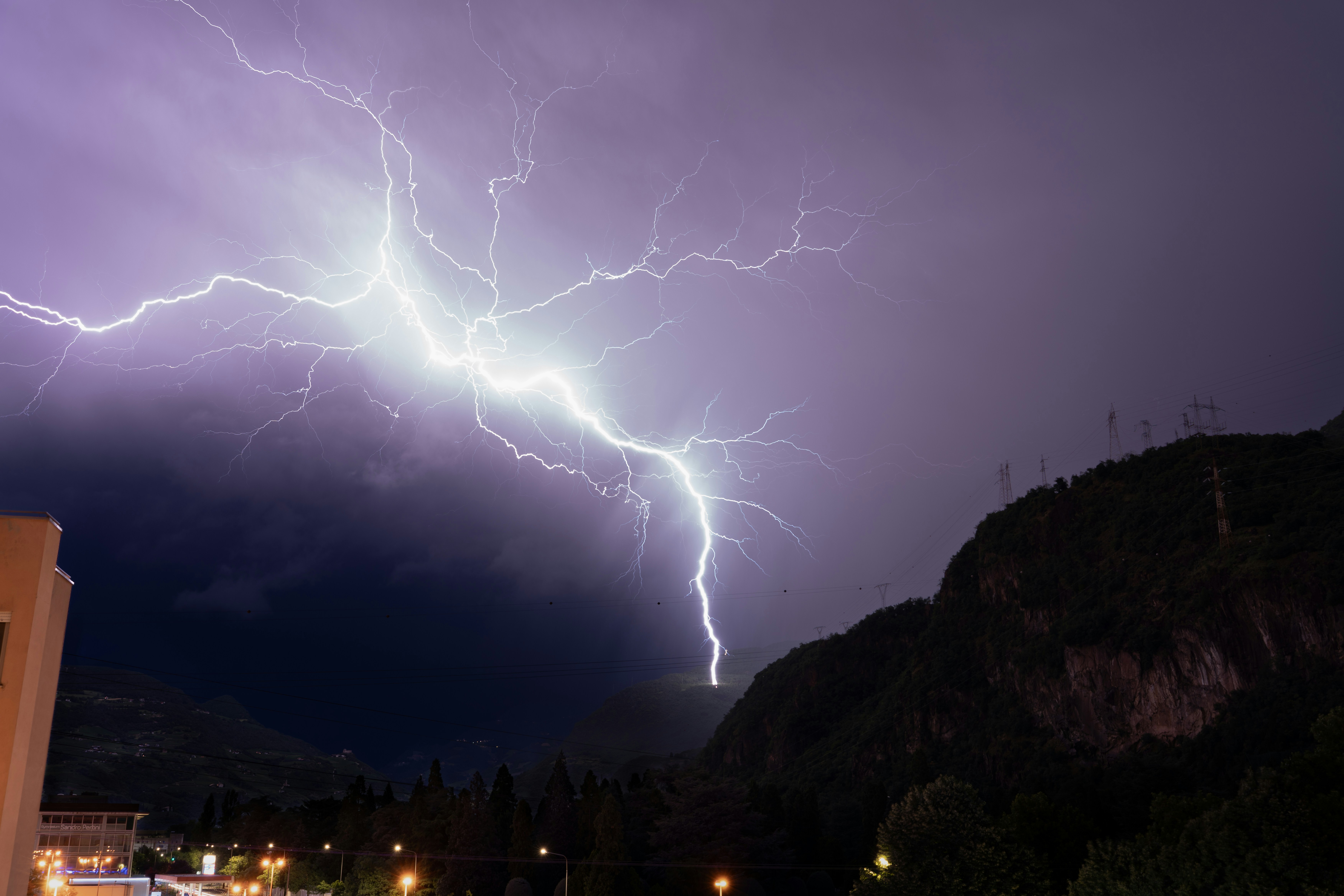 Lightning illuminates the night sky over mountains.