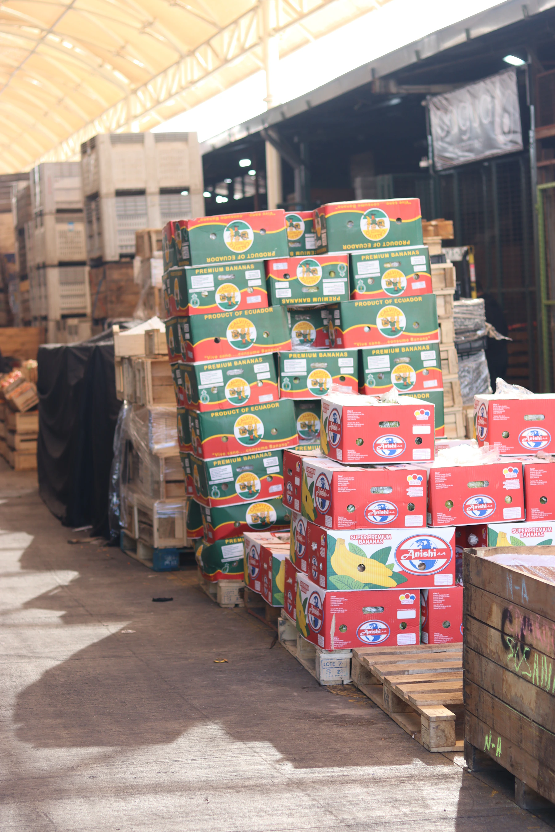 Pallets of labeled fresh produce cartons stacked at a wholesale distribution market awaiting refrigerated transport