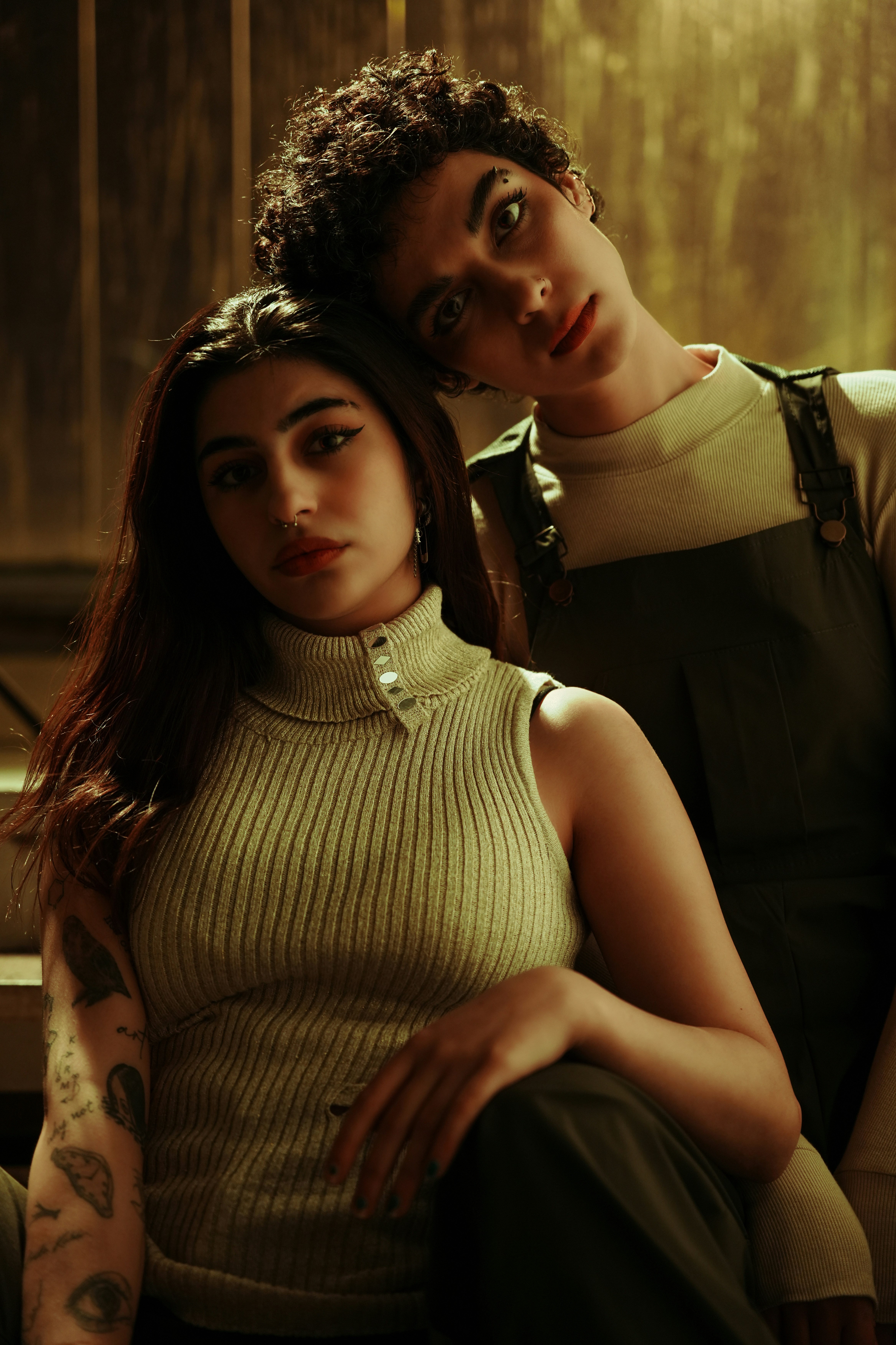 Two people pose closely for a stylish portrait