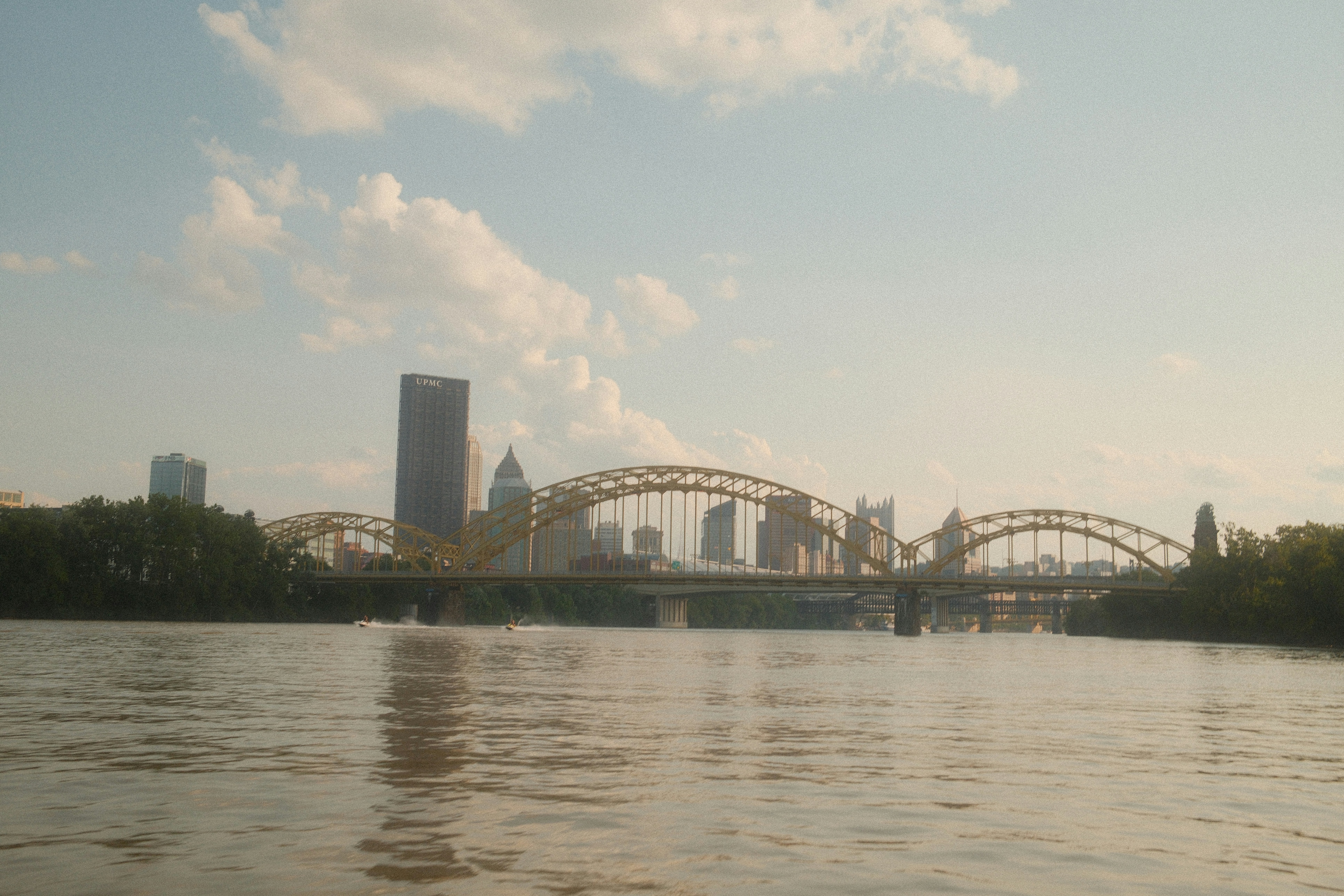 A bridge over a river with a city skyline.