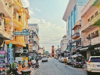 A sunny city street with shops and cars.