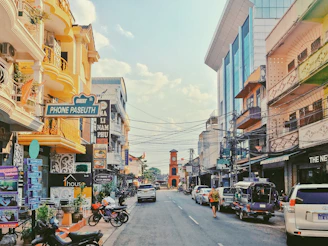 A sunny city street with shops and cars.
