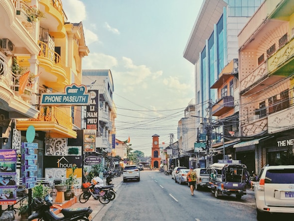 A sunny city street with shops and cars.