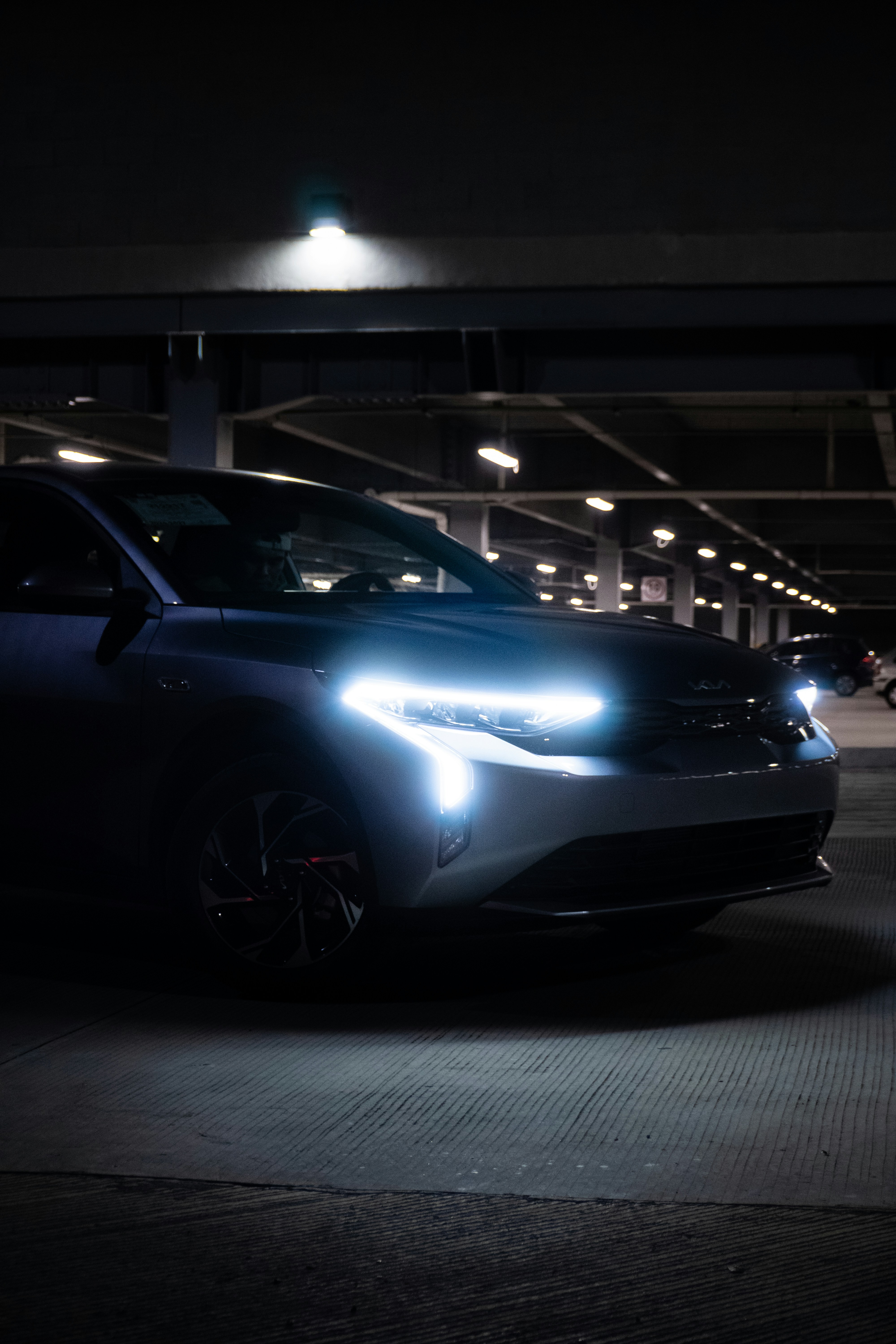 A car with bright headlights parked indoors.