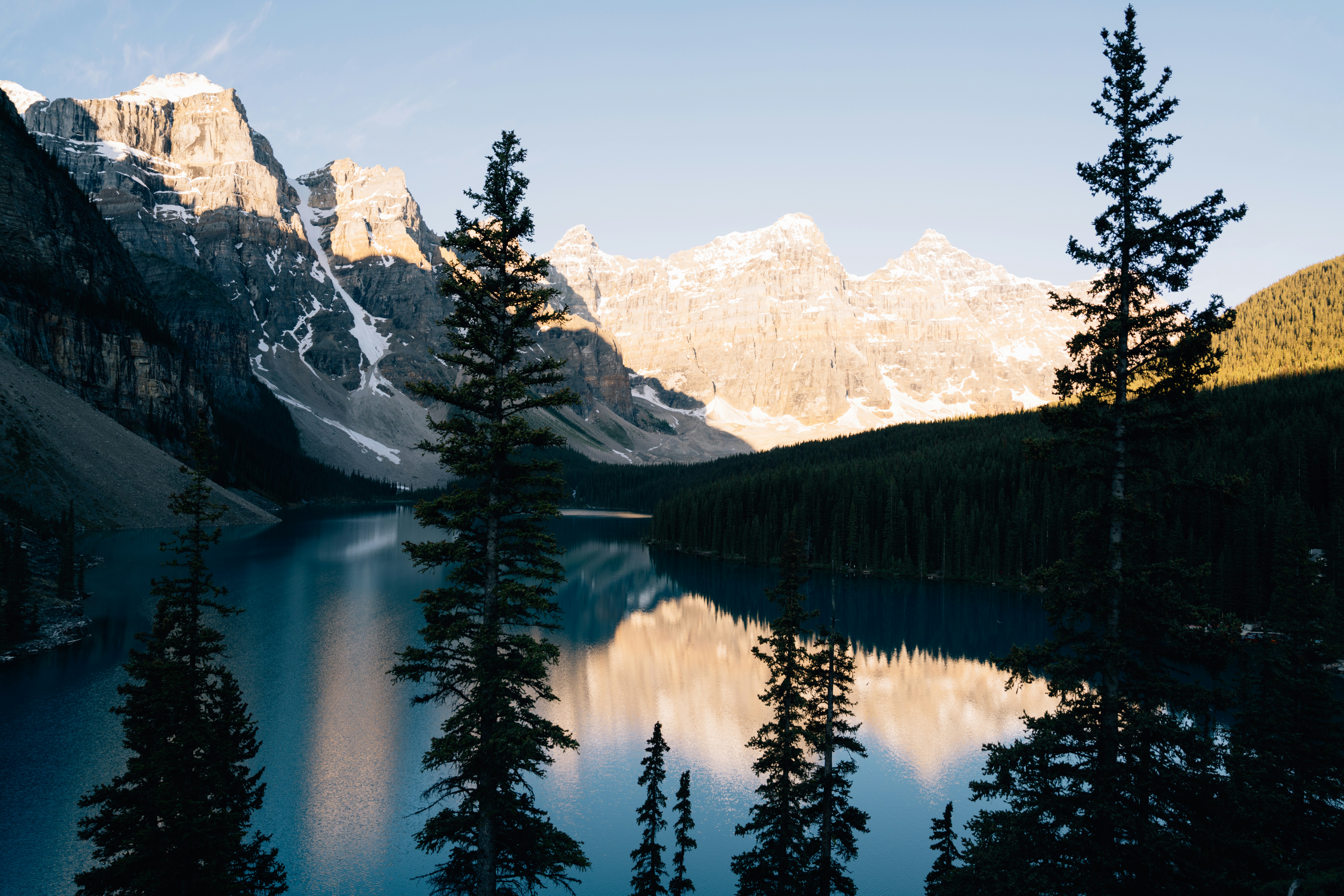 Mountains and trees reflected in a calm lake.