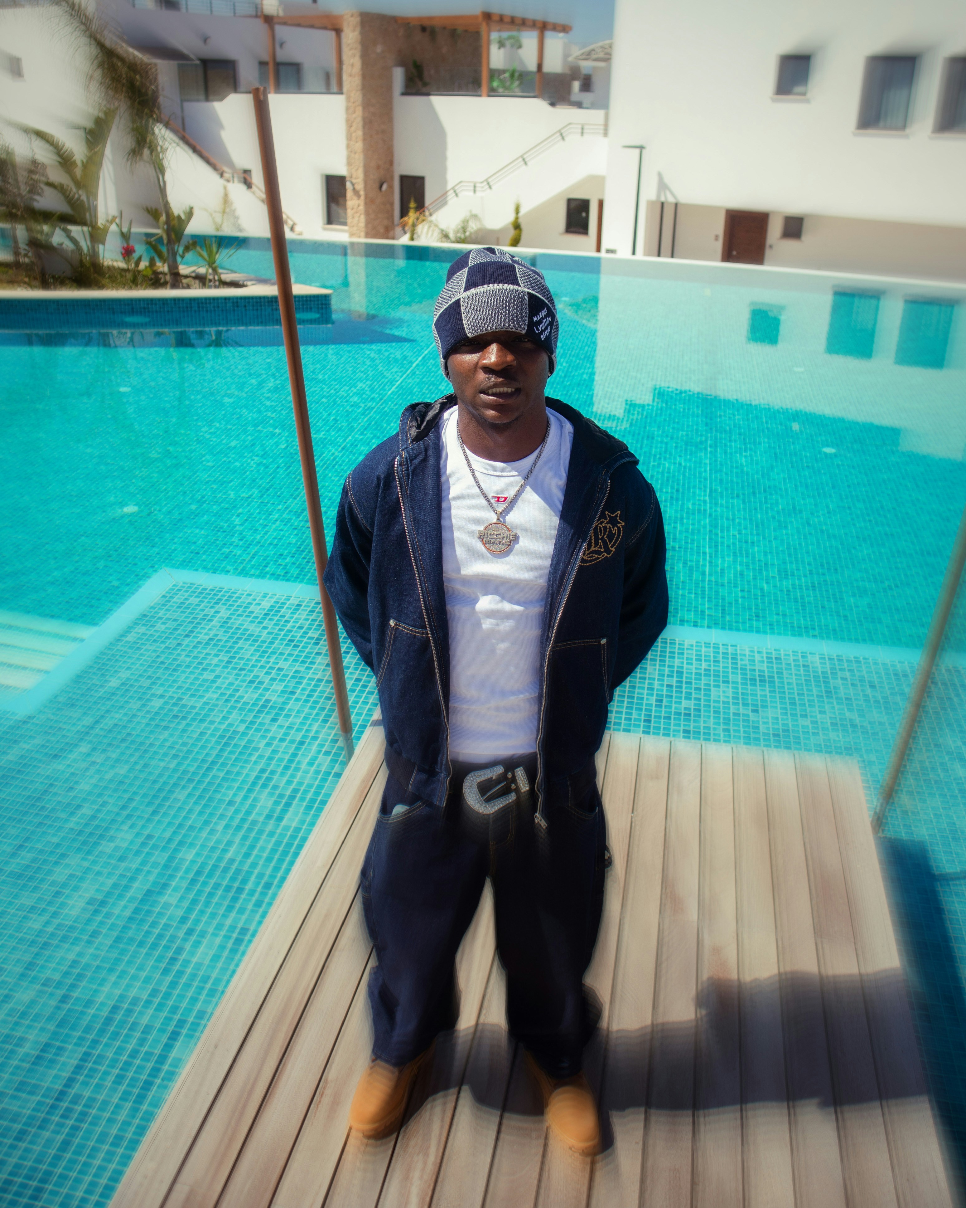 Man stands by a pool wearing a hat.