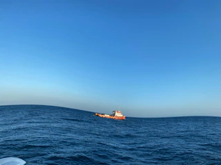 A boat floats on the ocean under a clear sky.