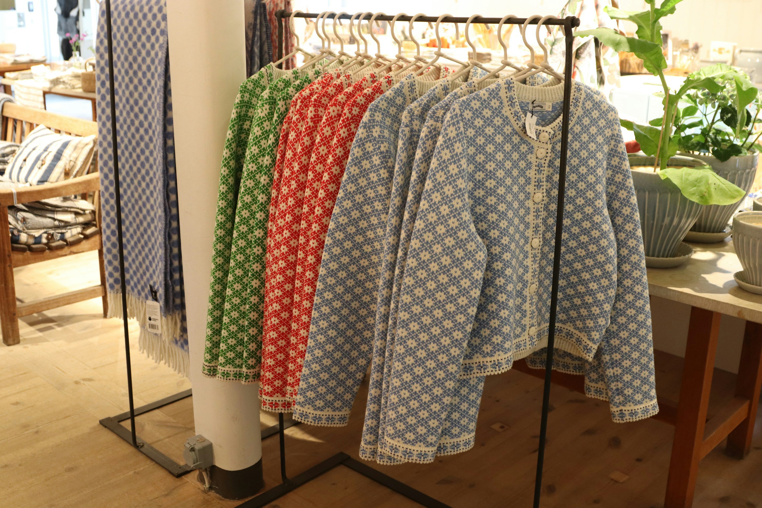 Colorful cardigans hang on display in a boutique.