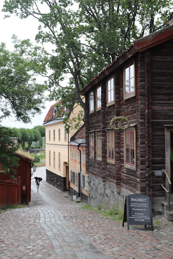 Cobblestone street leads past old wooden buildings.
