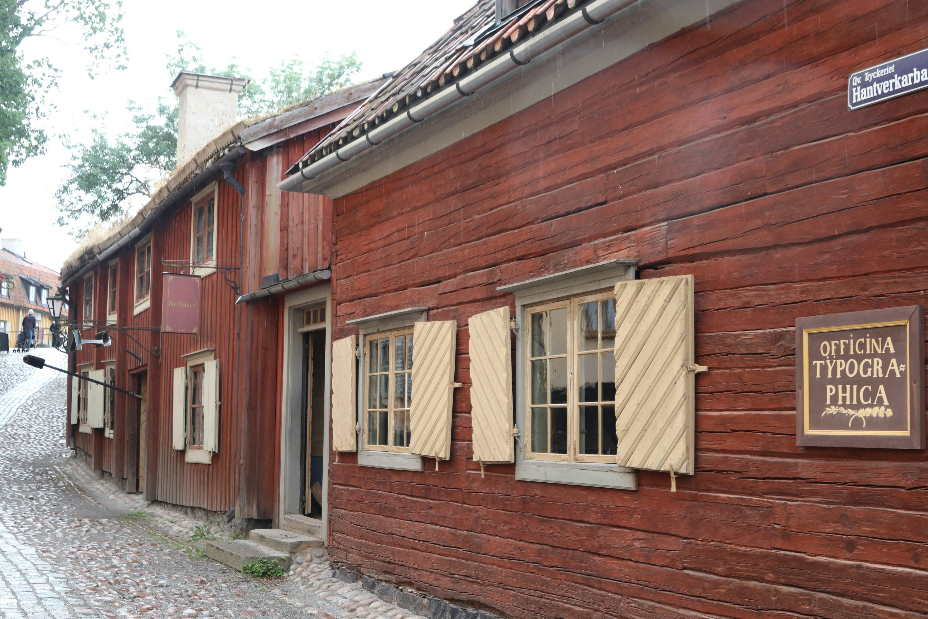 Red wooden buildings line a cobblestone street.