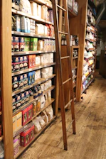 Shelves stocked with groceries and a ladder.
