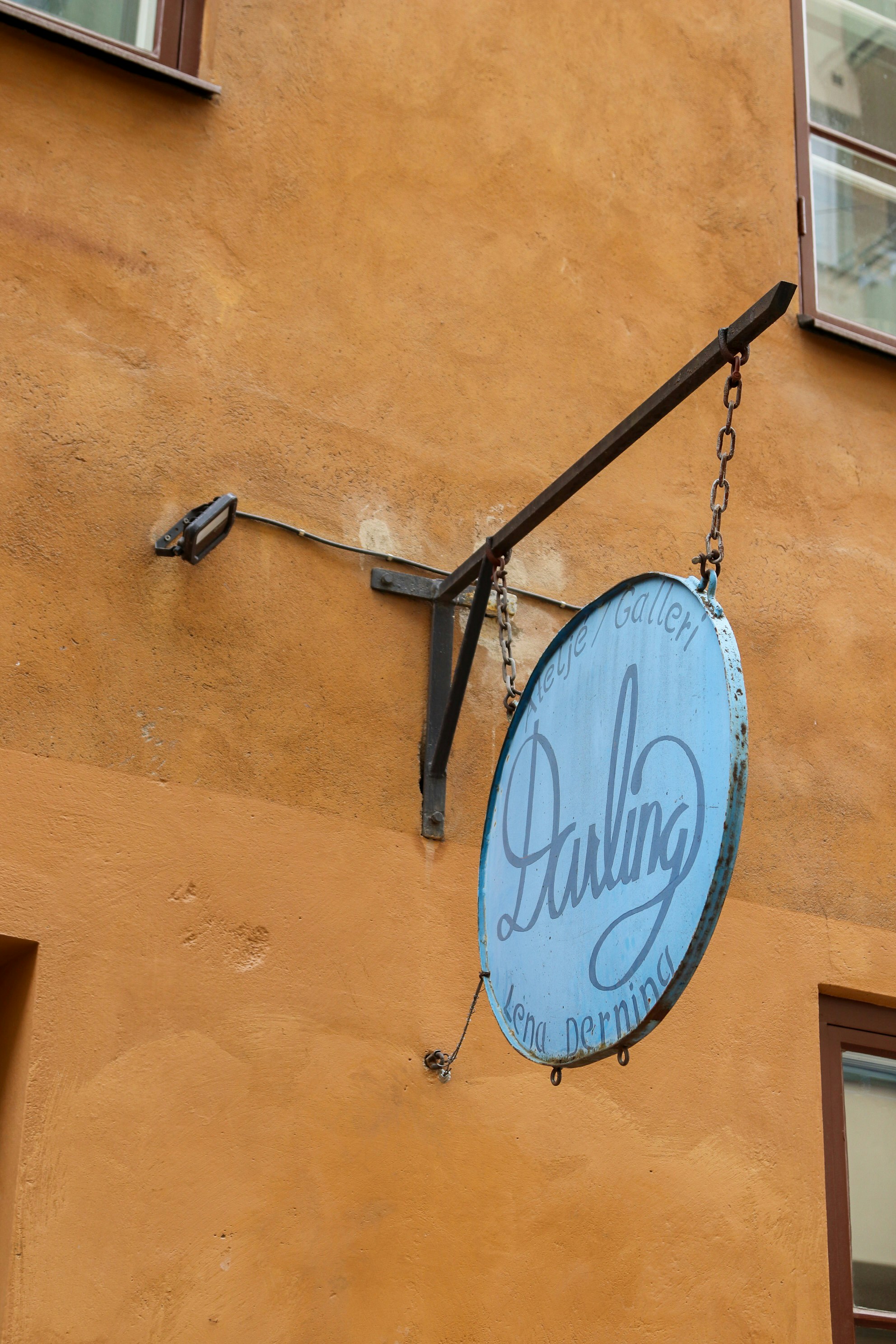 A blue sign hangs from an orange building.