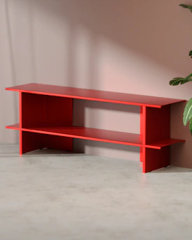 Red console table stands against a pink wall.