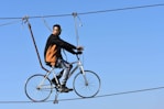 A man rides a bicycle across a tightrope.