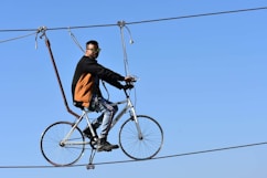 A man rides a bicycle across a tightrope.
