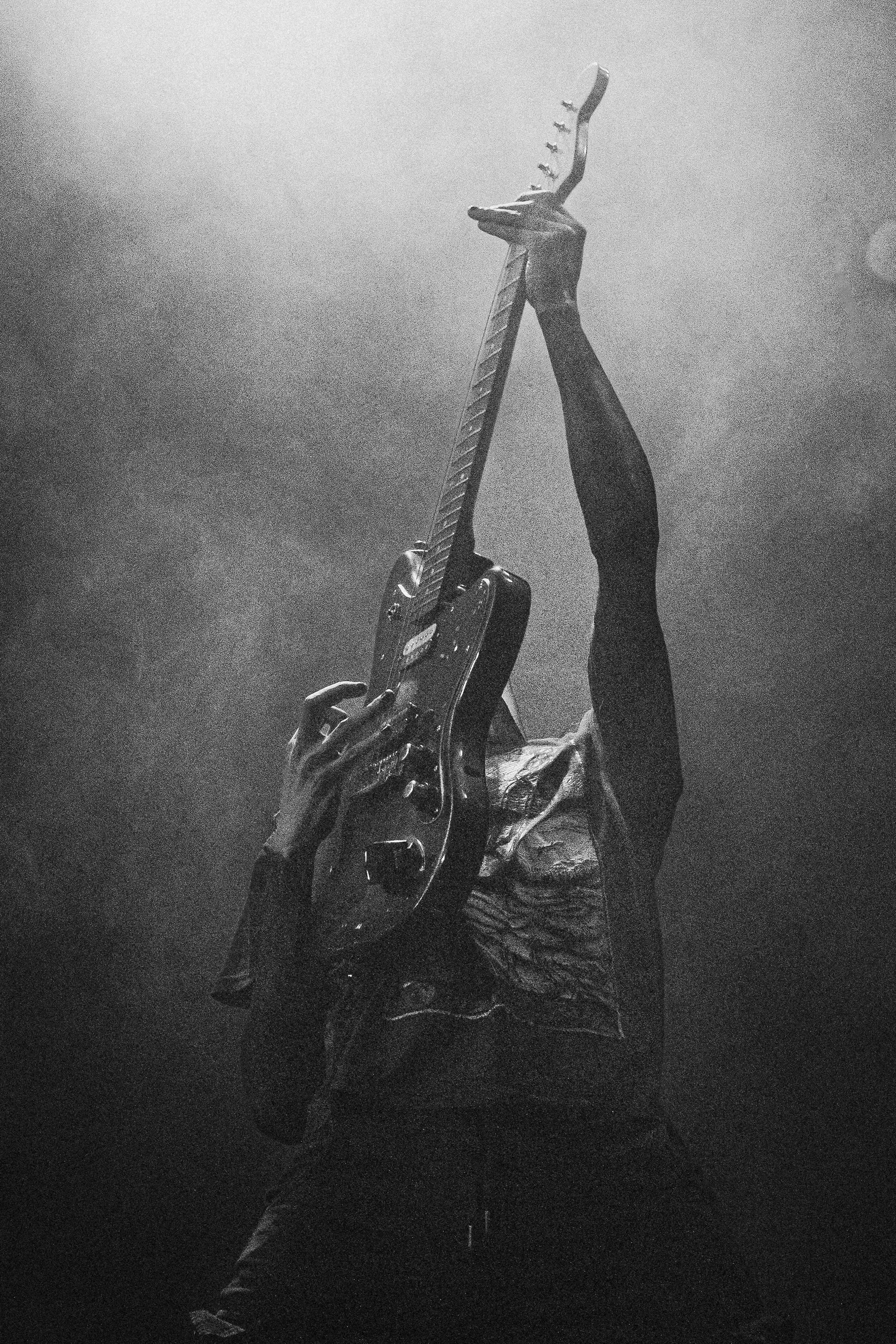 Grainy intensity as the guitar is raised high — a triumphant silhouette in monochrome fog. @pleia.band on Instagram