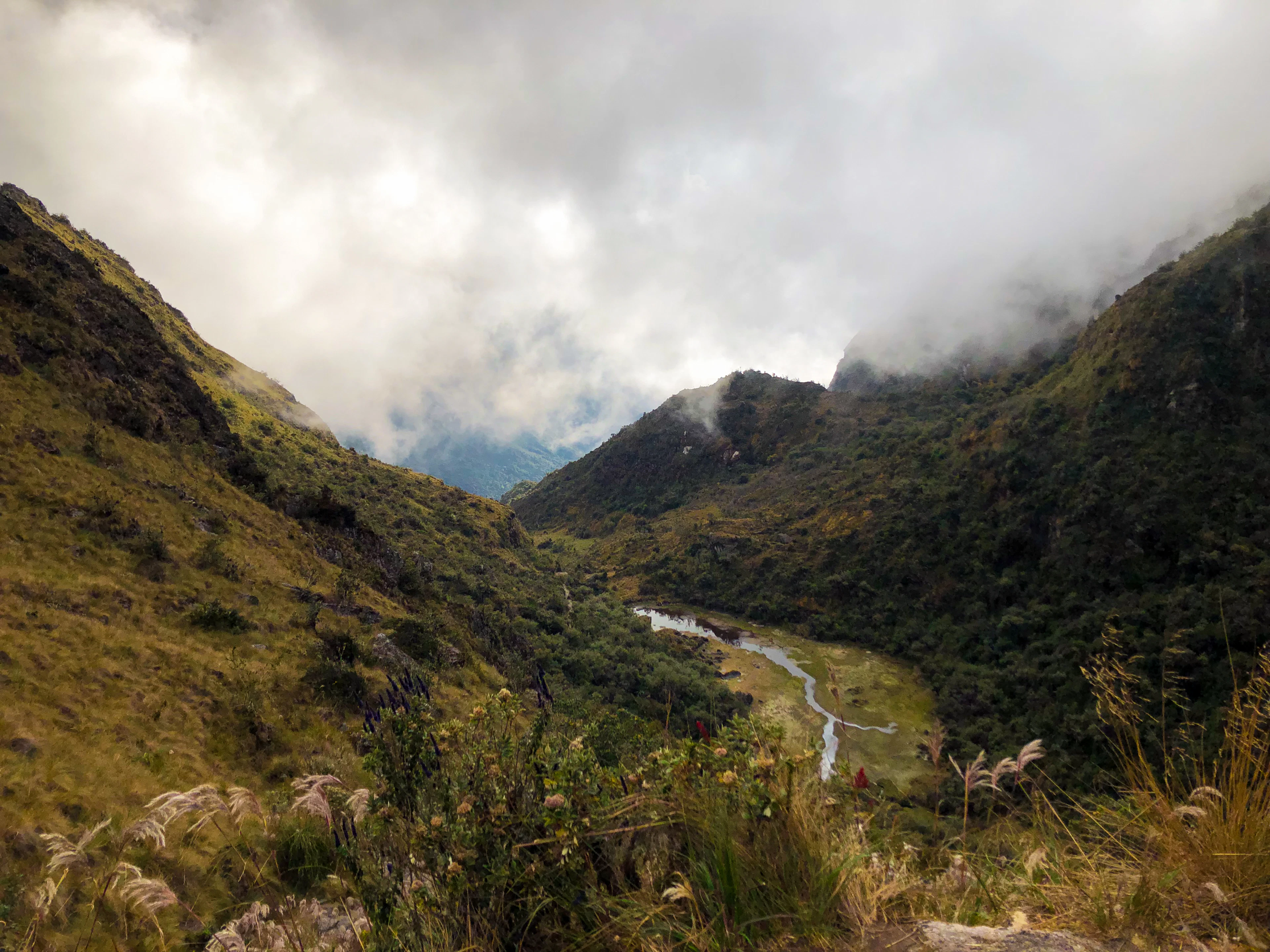 A winding river through a green mountain valley beneath the clouds on the Inca Trail, Peru