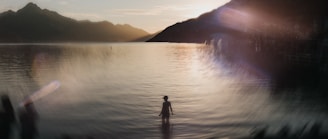 A person stands in the water at sunset.