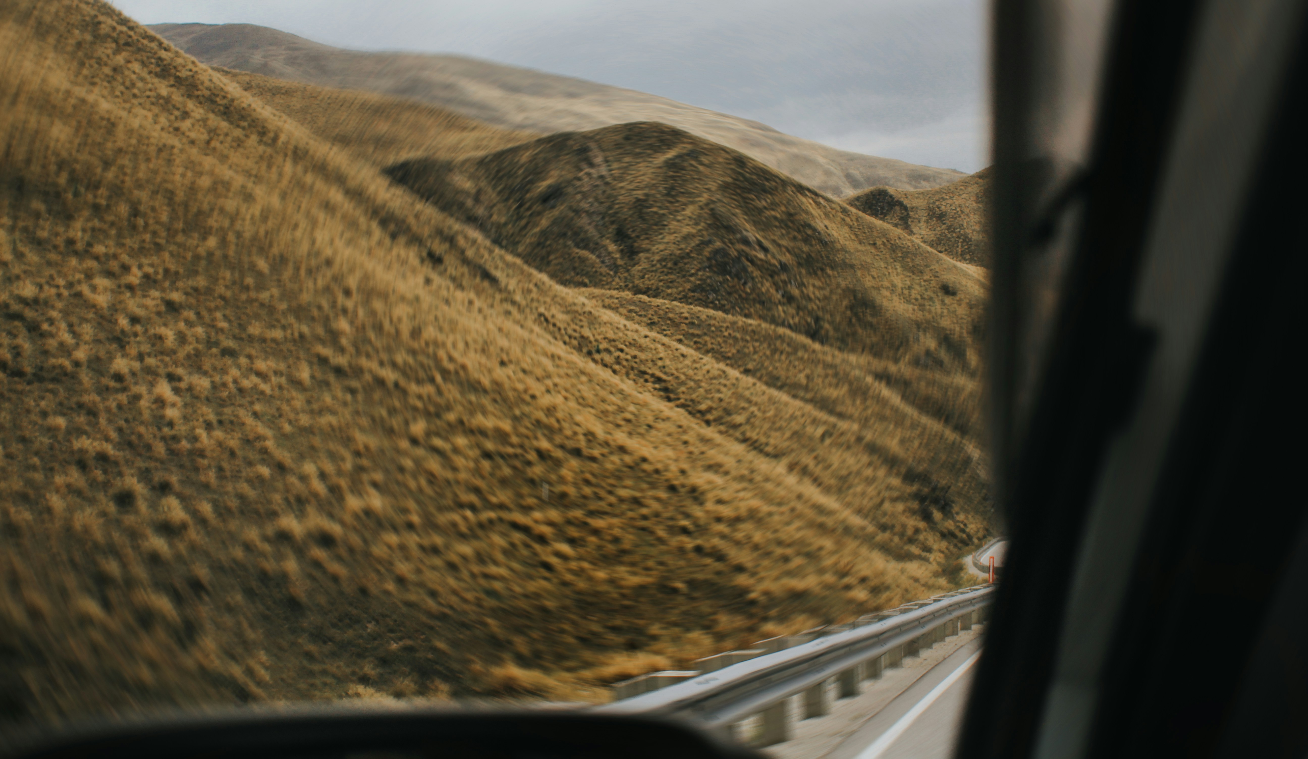 Driving past mountains on a cloudy day.
