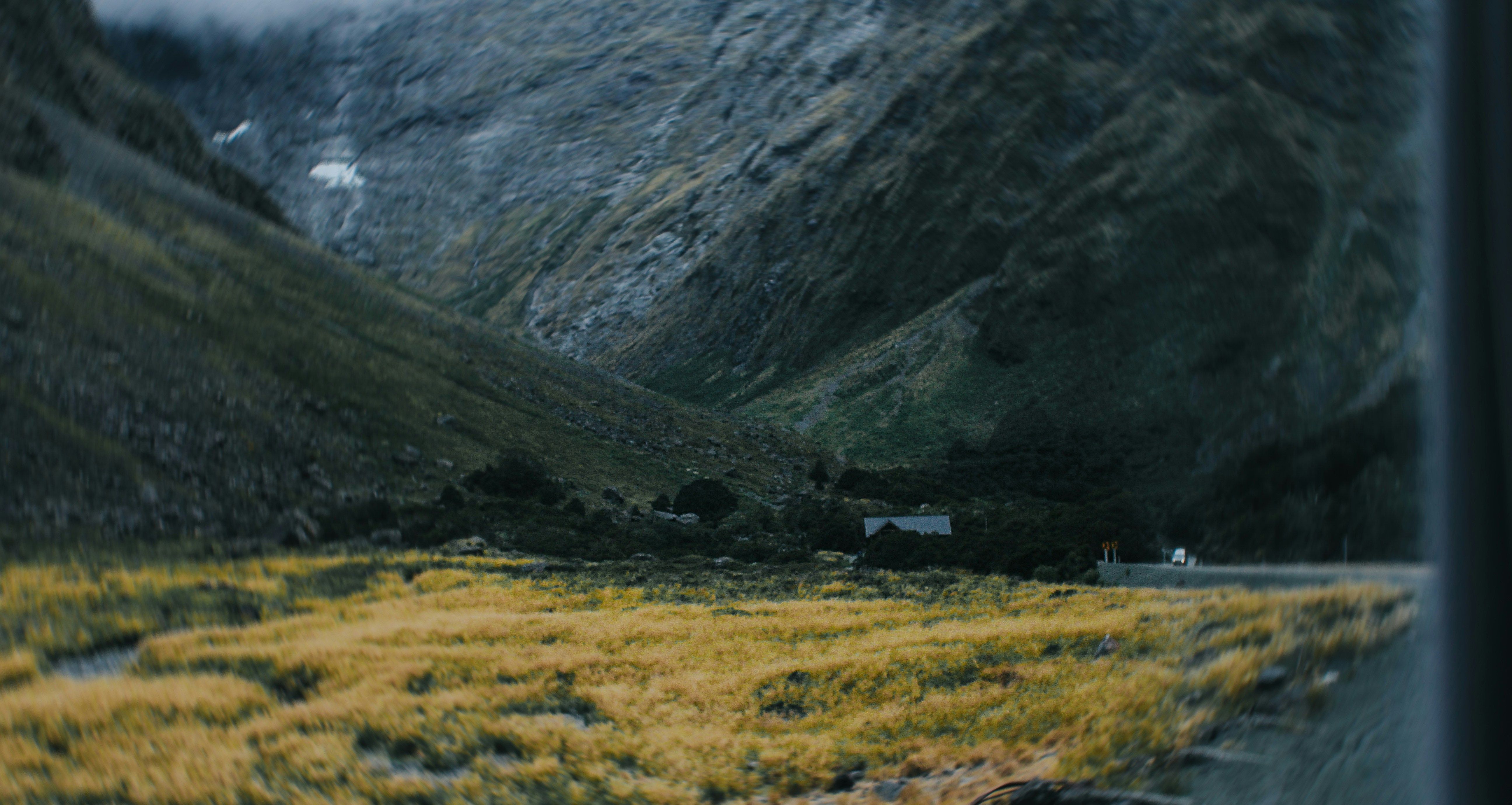 Mountains surround a cabin nestled amongst the fields.