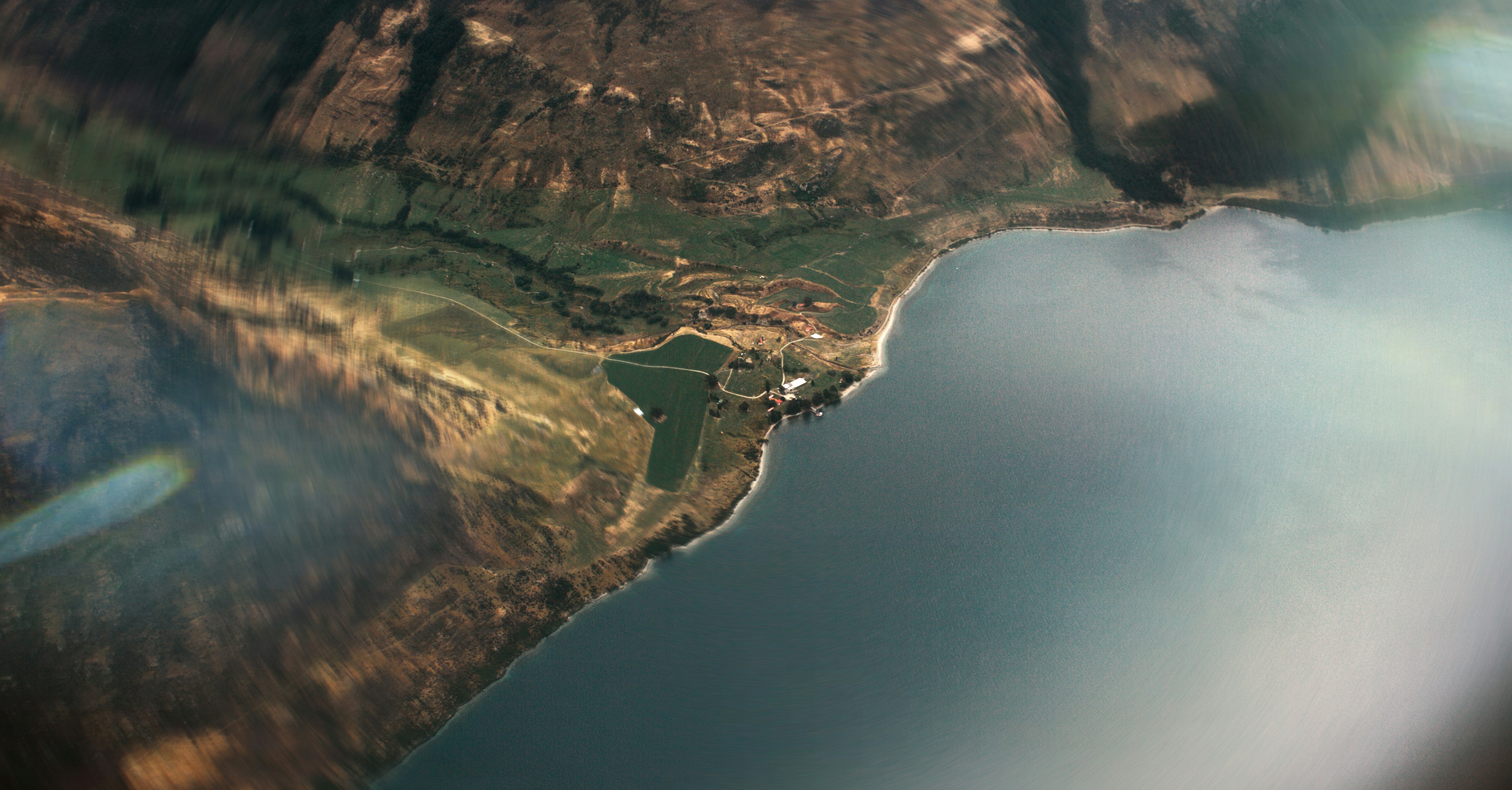 Aerial view of coastline, mountains, and a lake.