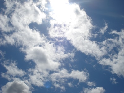 Bright sun shines through a cloudy blue sky.