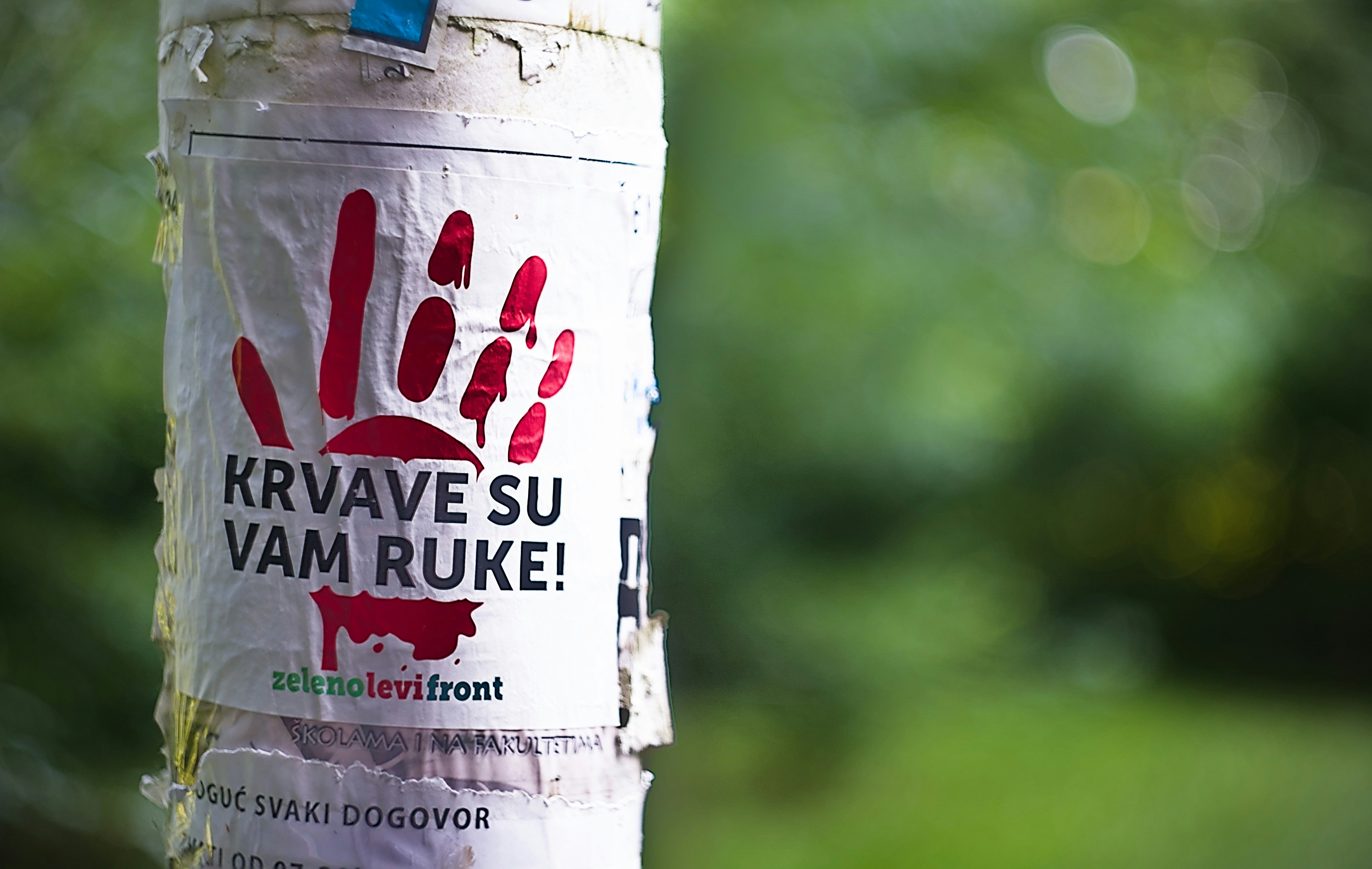 Bloody handprint poster with accusatory message.