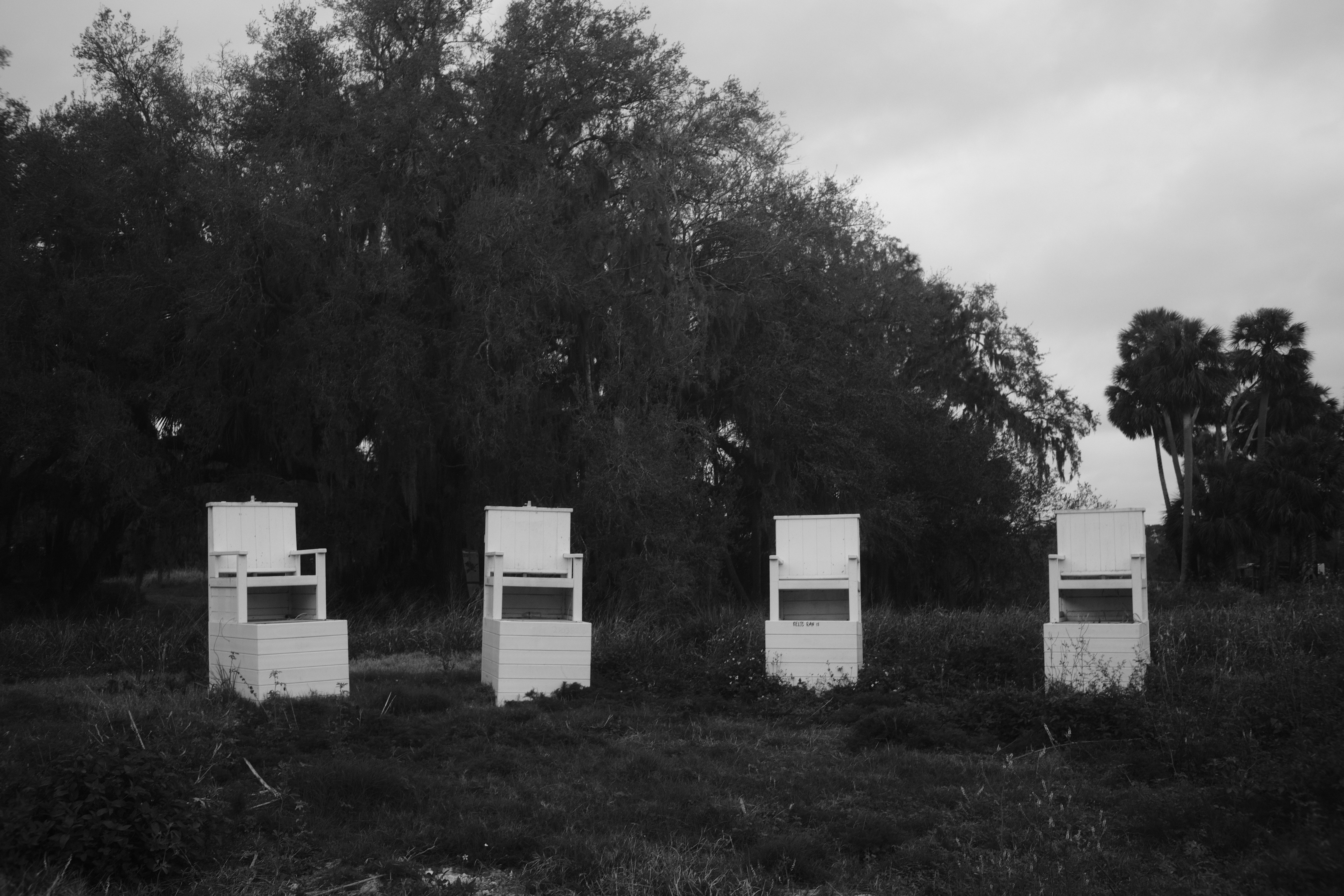 Four white structures stand in a field.