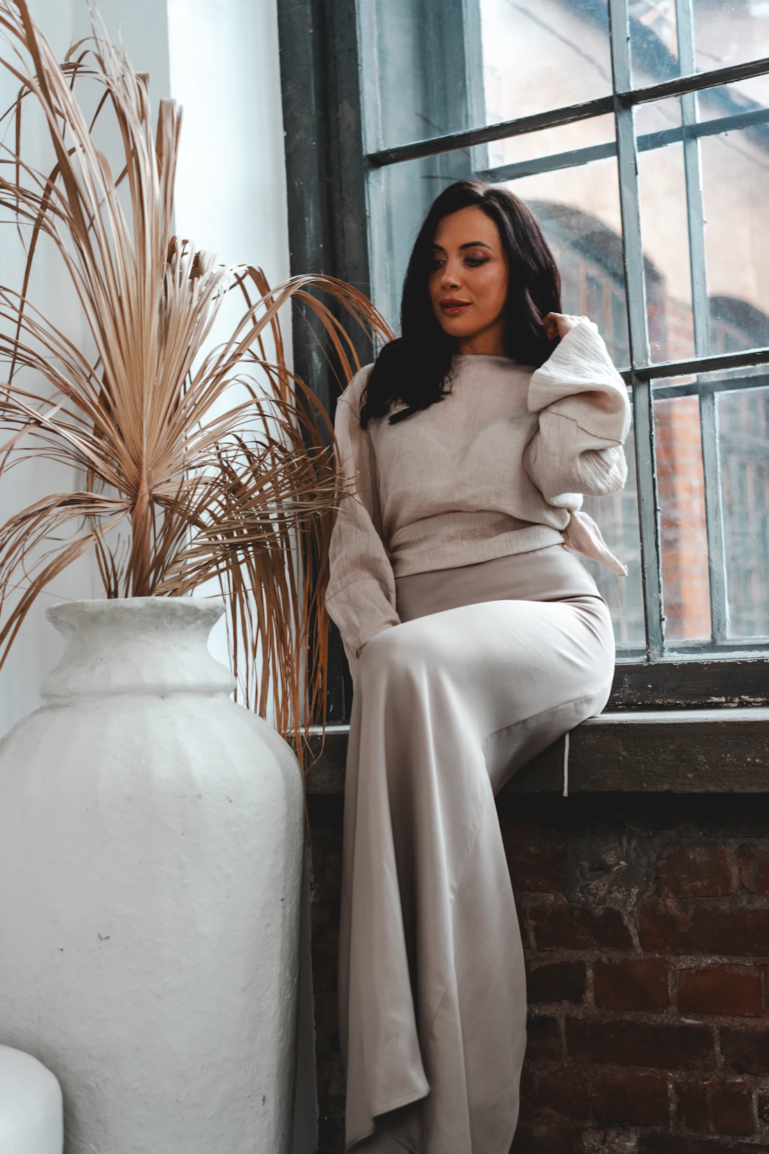 Model relaxing in neutral loungewear by a tall window