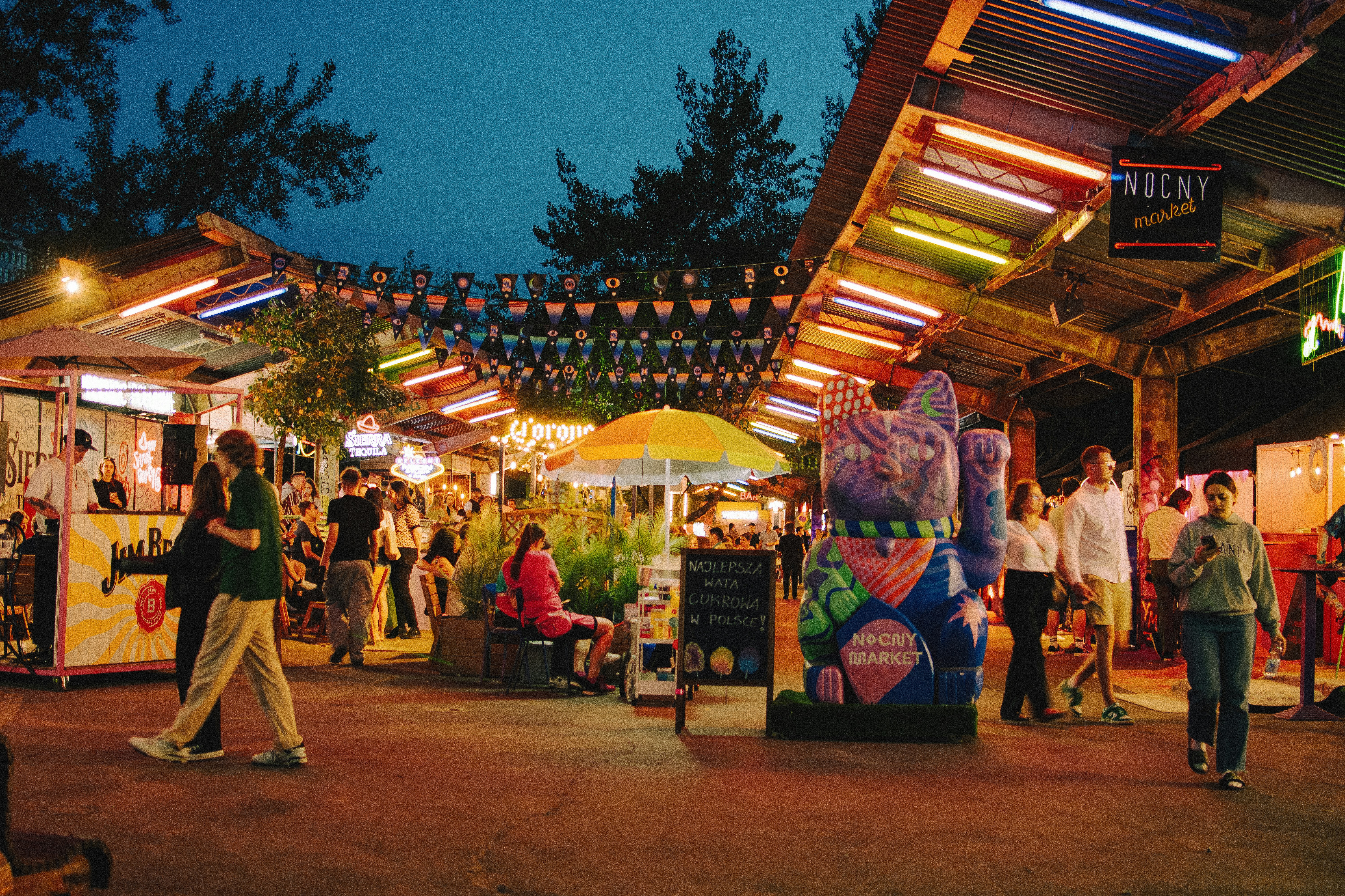 People enjoy food and drinks at an outdoor market.