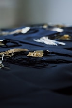 Graduation tassels rest on a dark, blue cloth.