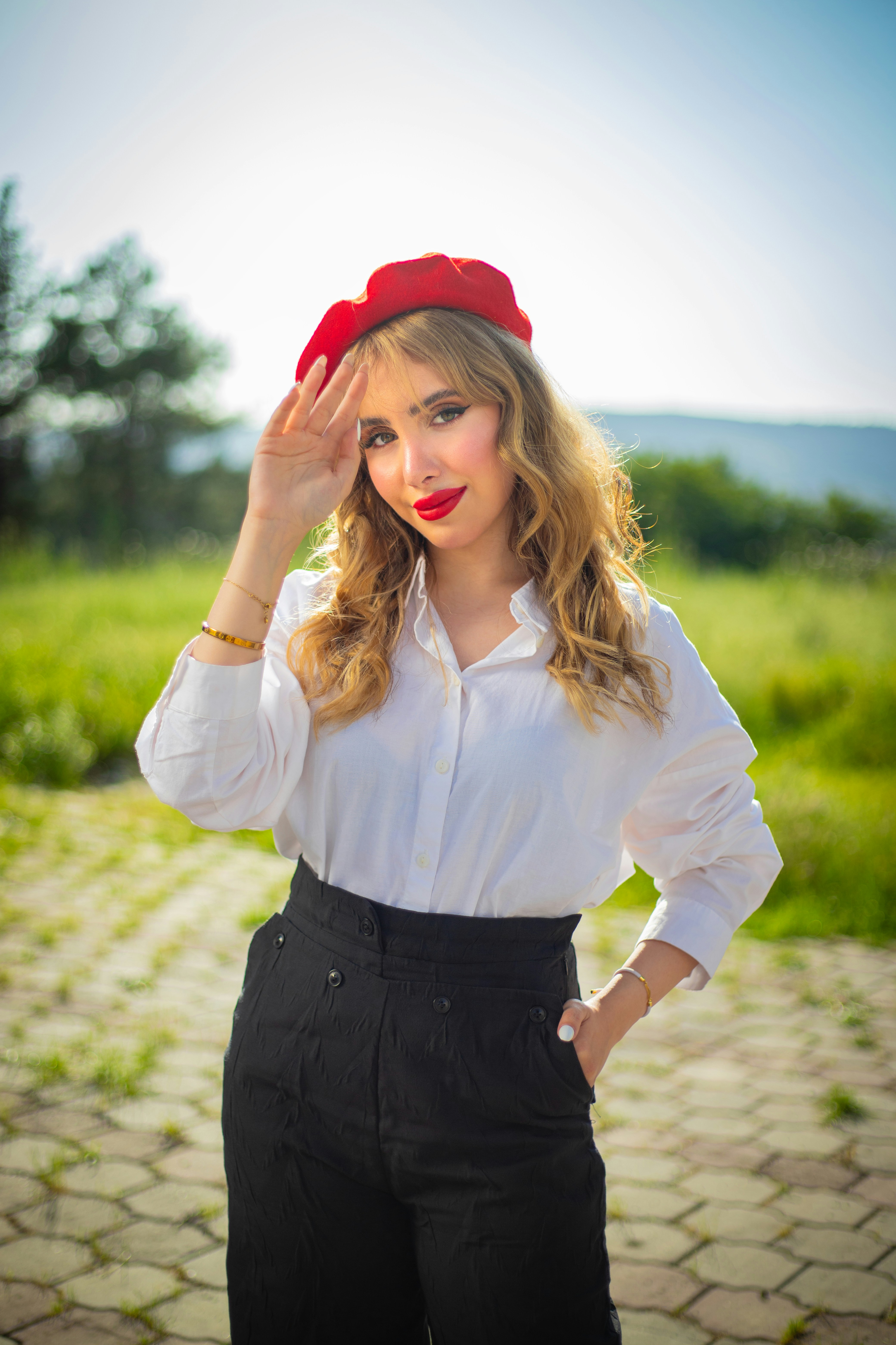 Femme élégante en béret rouge pose à l’extérieur.