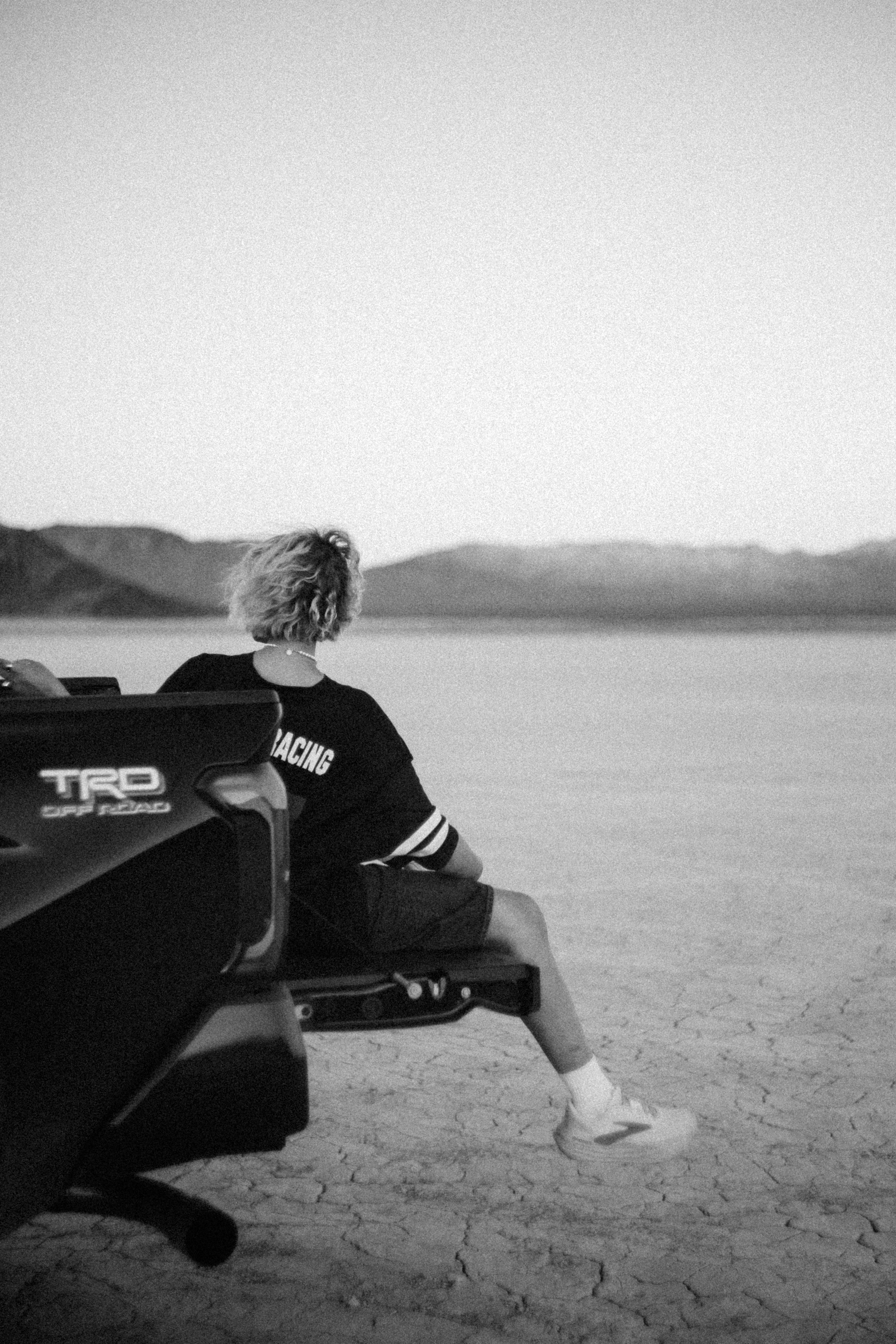A person sits on a truck bed, looking at the landscape