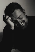 A smiling man leans on his hand.