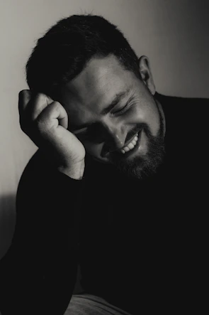A smiling man leans on his hand.