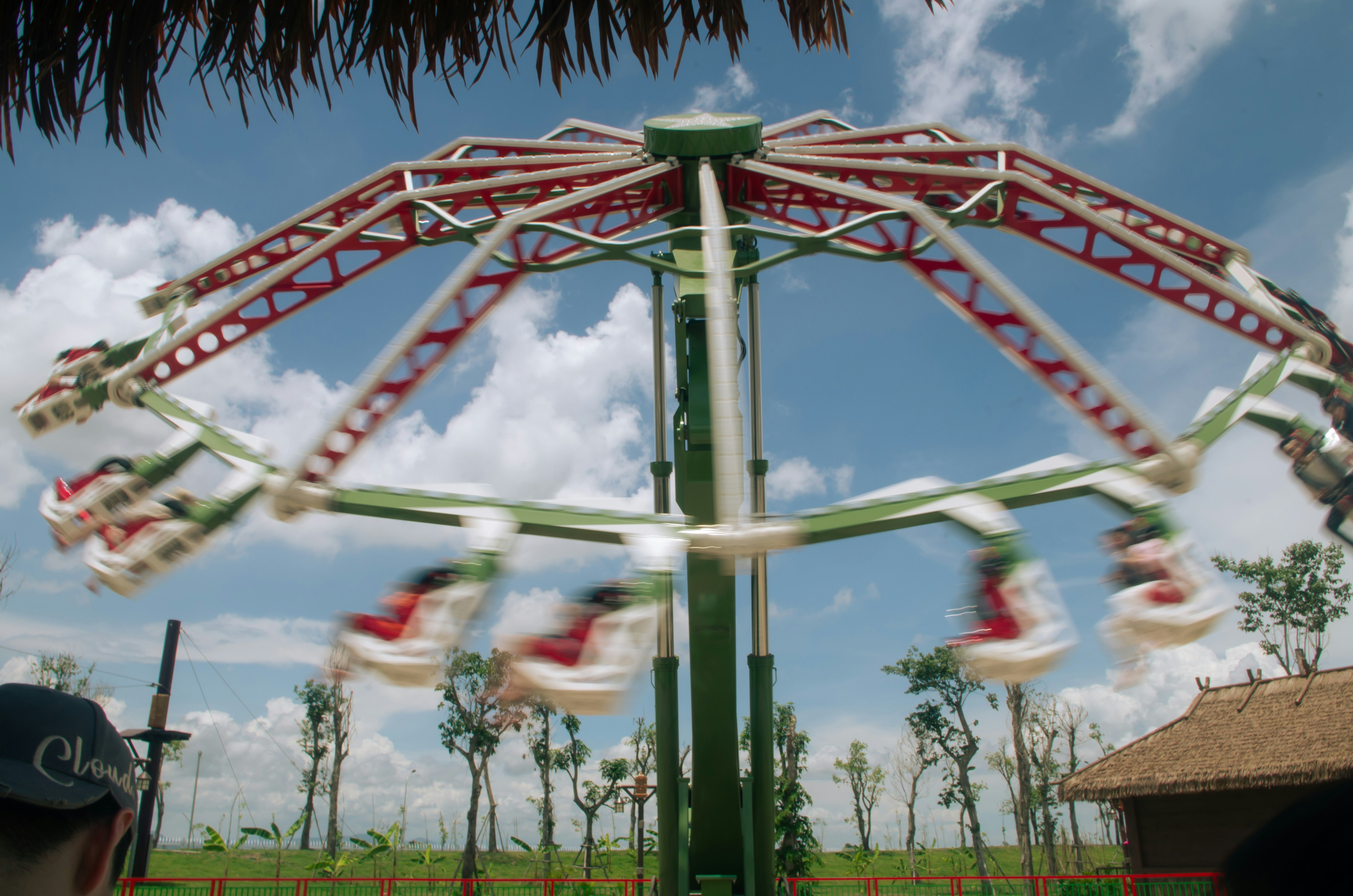 A swirling ride spins around under a blue sky.