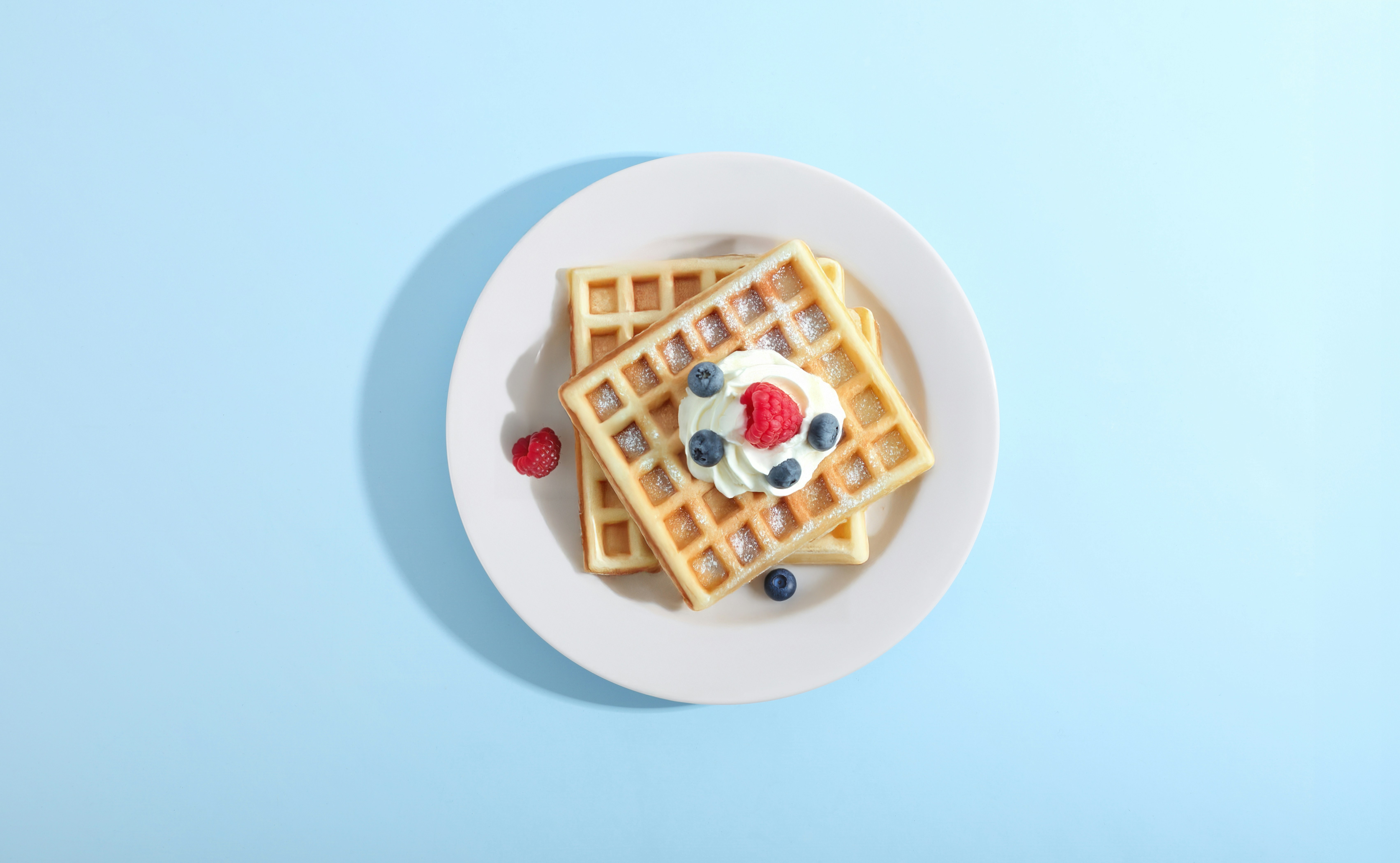 Waffles with berries and cream on a plate.