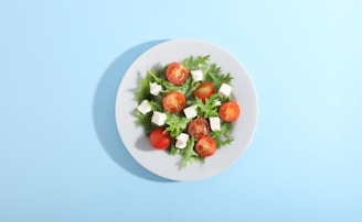 A plate of fresh salad with tomatoes and cheese.
