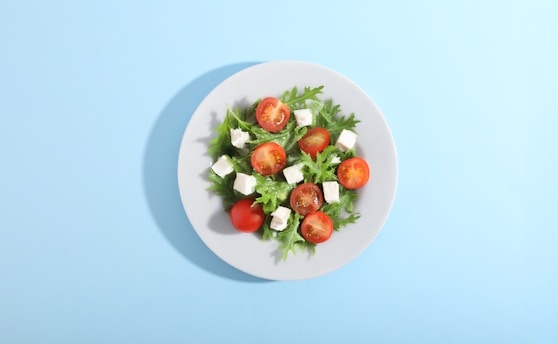 A plate of fresh salad with tomatoes and cheese.