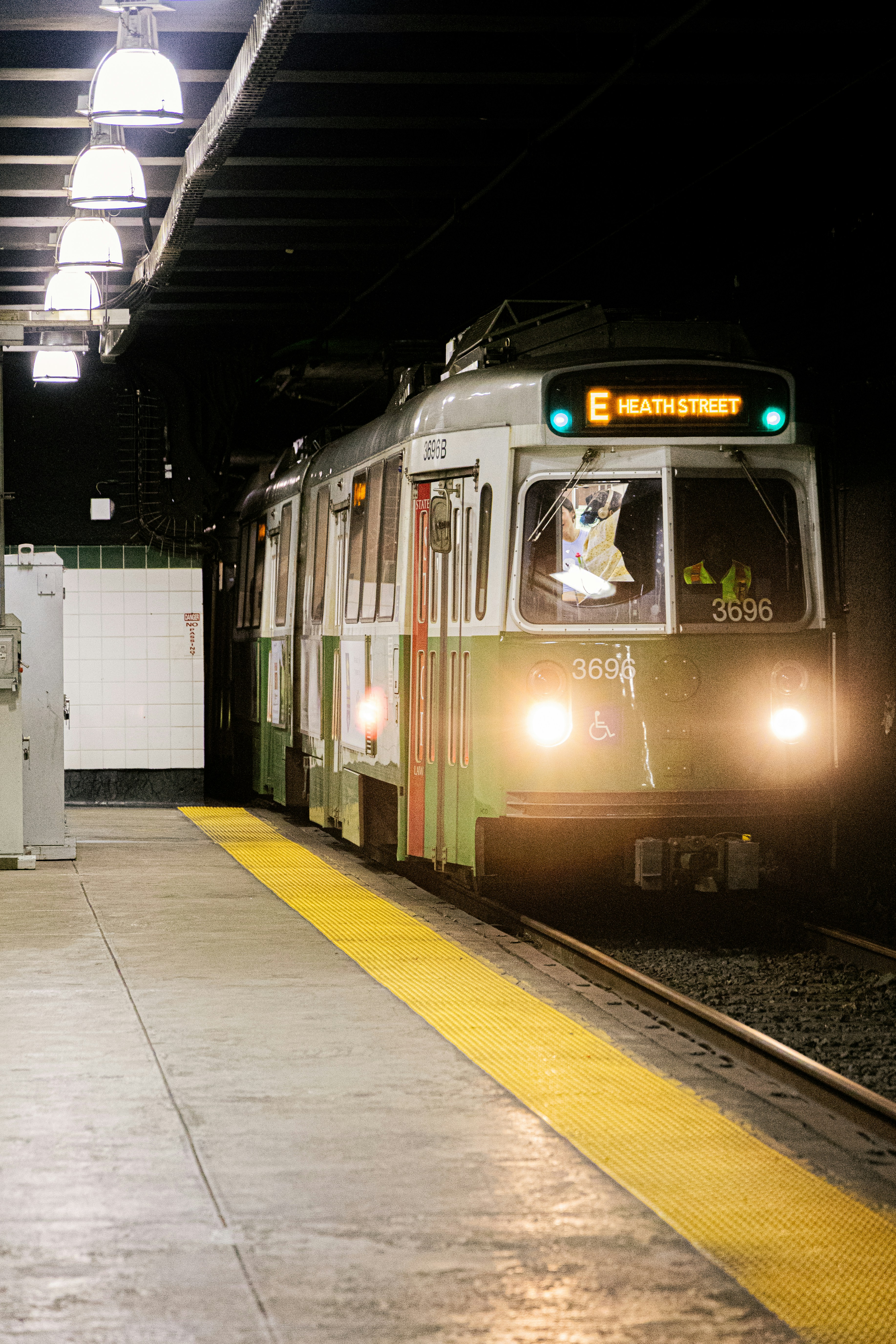 An mbta train pulls into a dimly lit station.