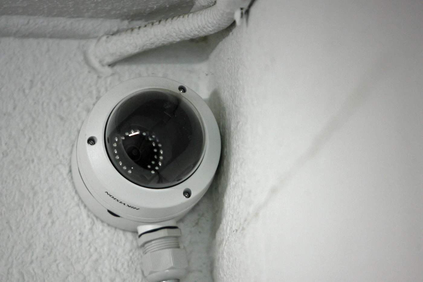 Close-up of a white dome security camera mounted on a ceiling