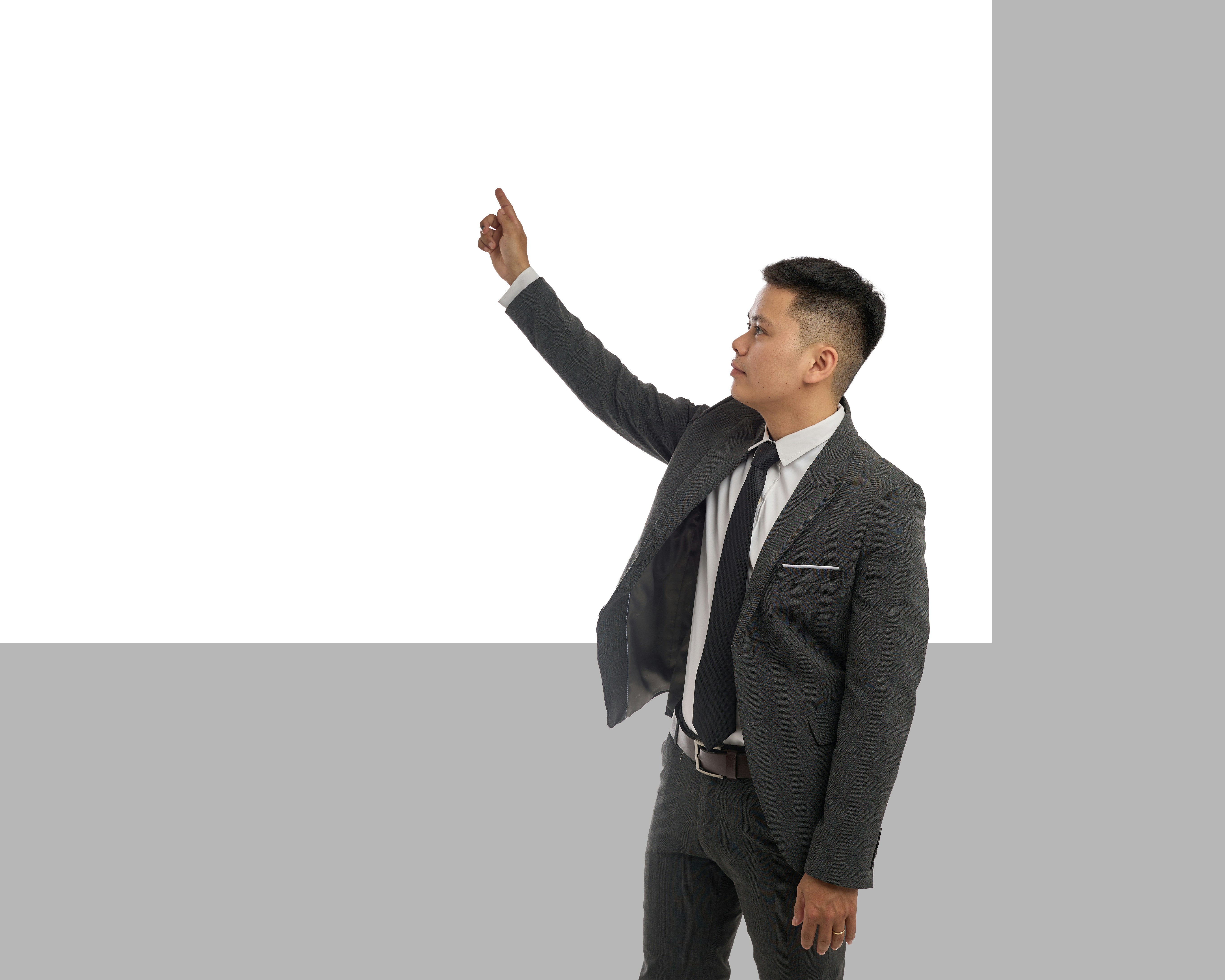A businessman points upward at a blank screen.