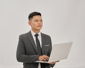 A businessman is holding a laptop and looking up.